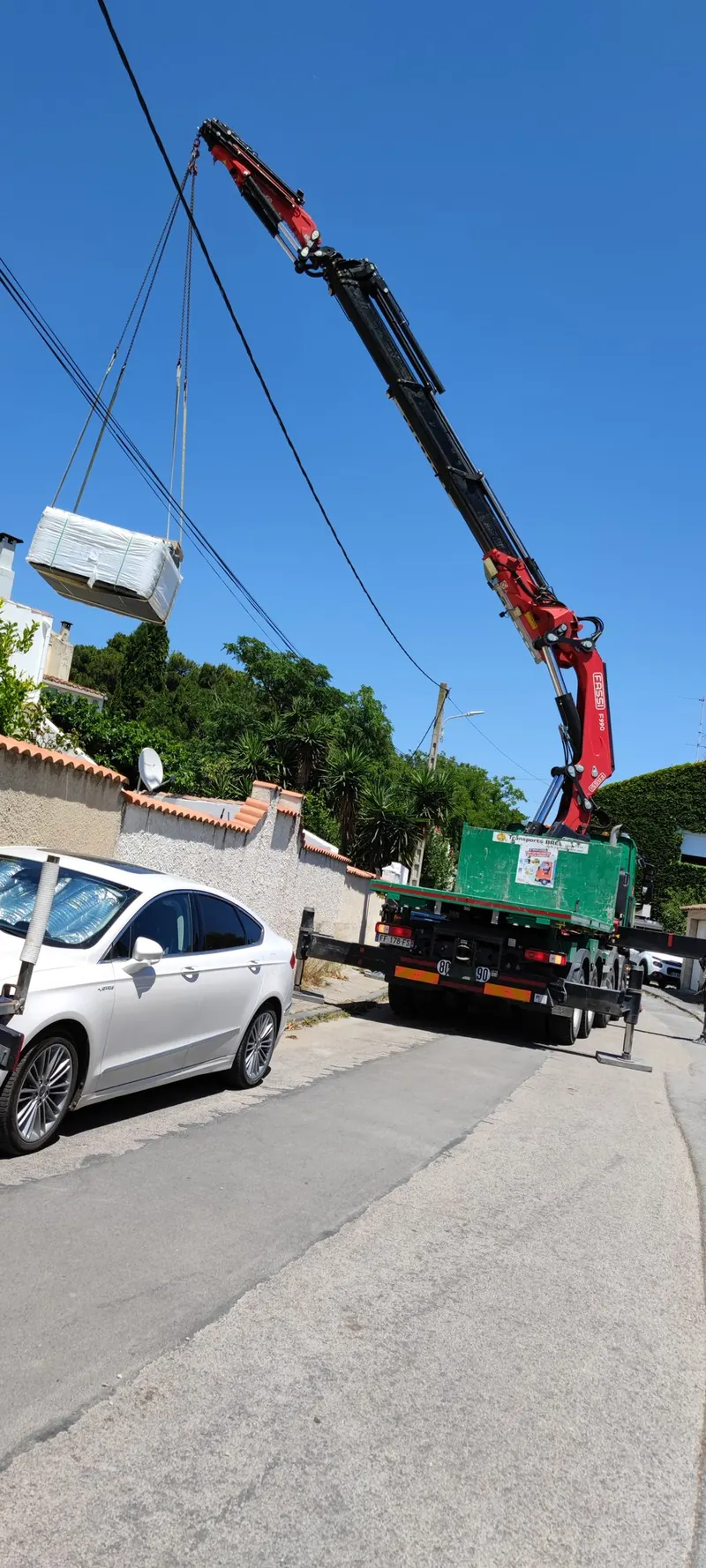 Grue soulevant un caisson blanc, en suspension