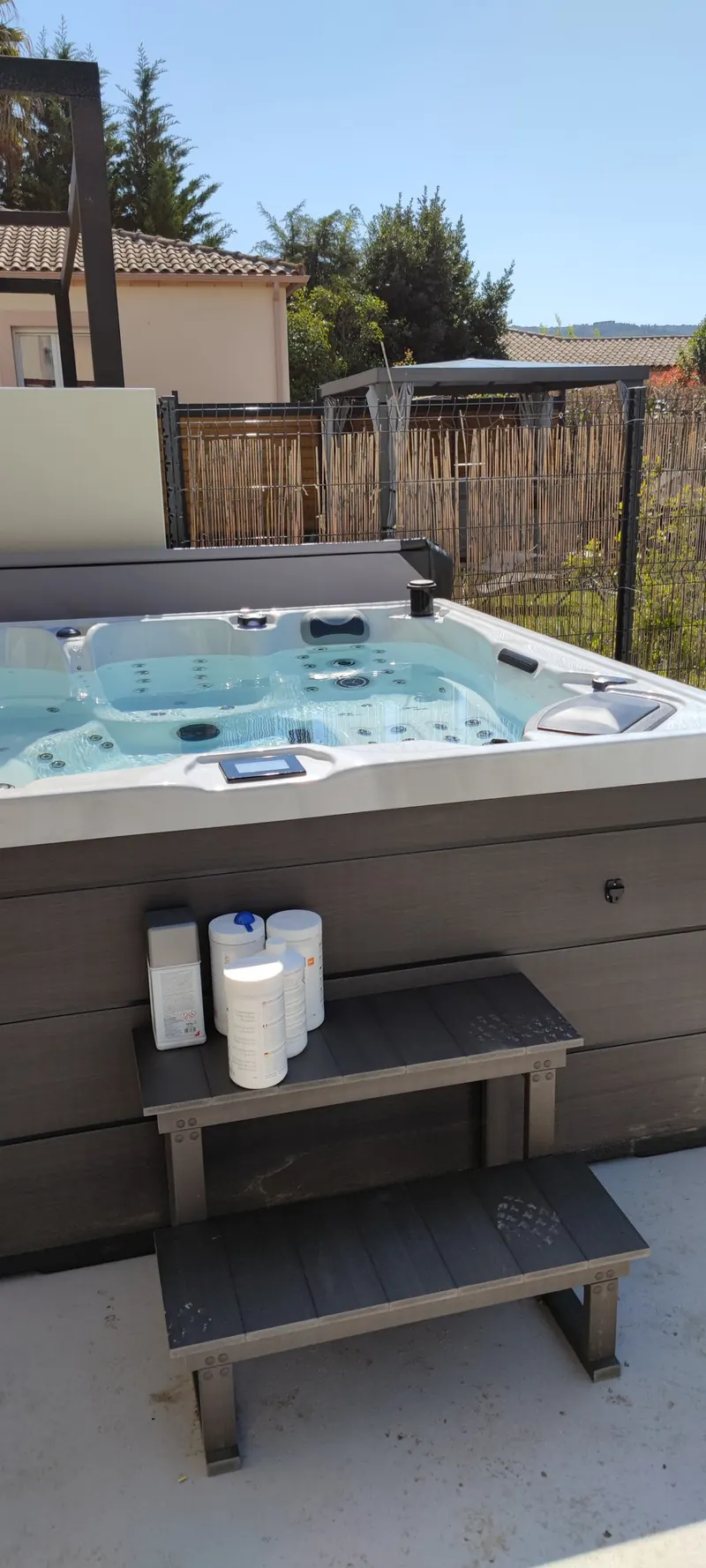 Spa blanc vu de trois-quarts, commandes en façade, terrasse bétonnée