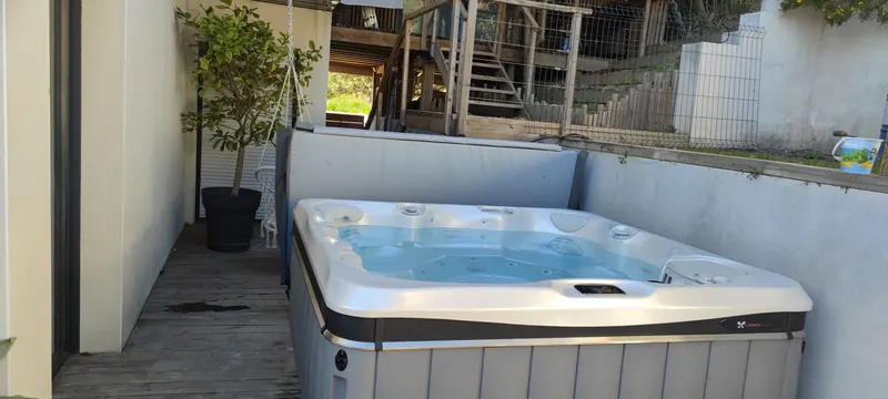 Spa en retrait sur la terrasse, devant une structure en bois surélevée
