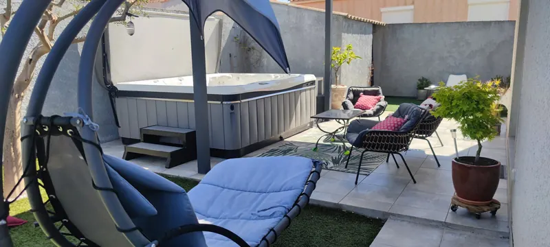 Spa installé entre le mobilier de détente et la piscine
