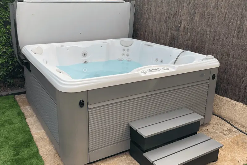 Spa rempli avec son marchepied gris à deux marches devant l'habillage