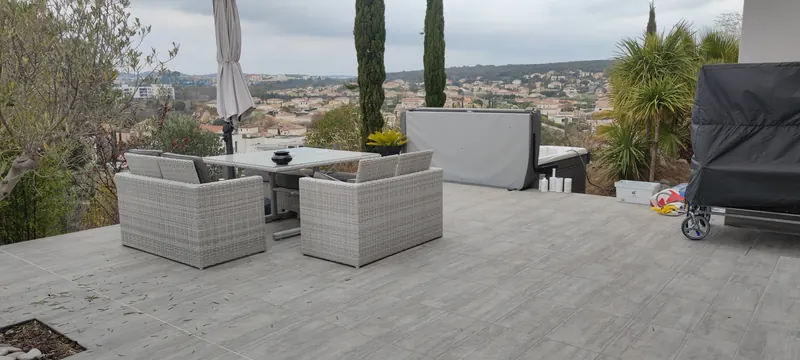 Terrasse aménagée : mobilier en rotin, spa fermé au fond, parasol et vue dégagée
