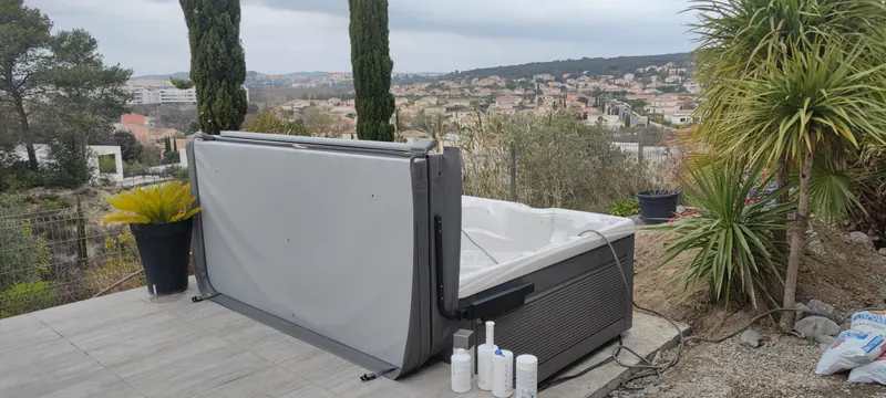 Fauteuils en rotin face au spa blanc fermé, avec parasol et plantes