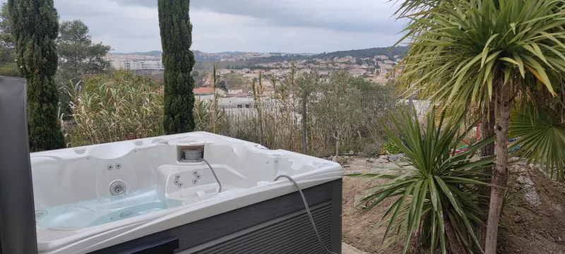 Spa découvert à l'eau turquoise, jets visibles, vue panoramique sur la ville
