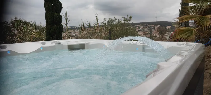 Vue plongeante sur le spa rempli : eau turquoise, jets et équipements