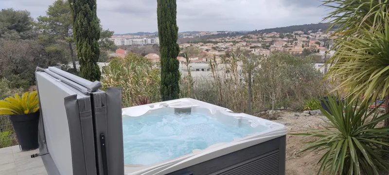 Côté du spa : eau turquoise, câbles et flacons de produits de traitement