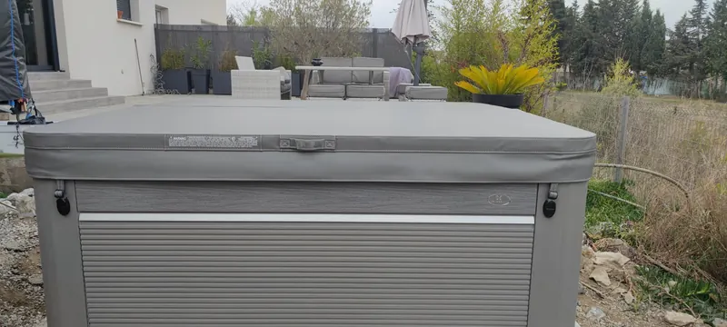 Spa fermé sous sa couverture grise, vu de trois quarts