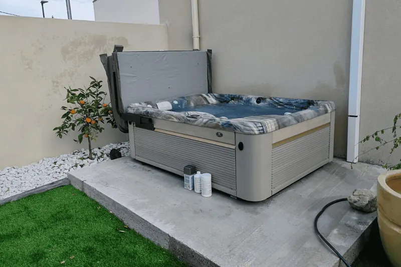 Petit jardin de Poussan avec gazon synthétique et spa Caldera Kauaï sur sa dalle
