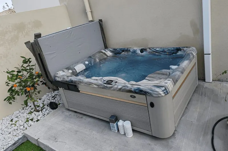 Spa Caldera Kauaï en eau sur une dalle en béton dans un petit jardin de Poussan