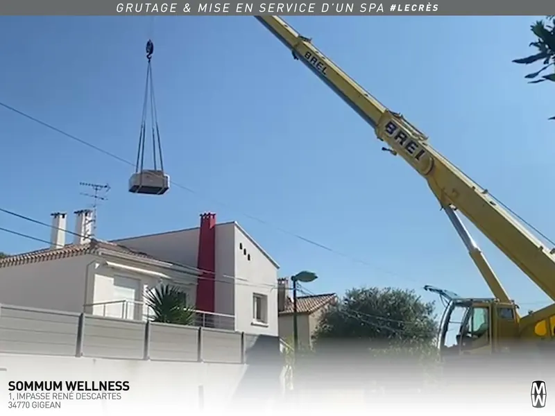Grue jaune soulevant le spa au-dessus d'une maison du Crès