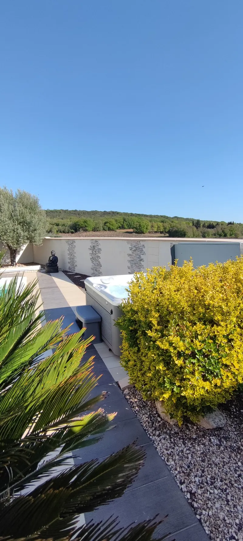 Spa près de la piscine turquoise, mur de clôture blanc et palmiers