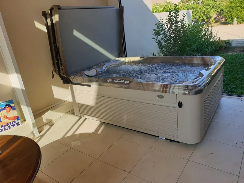Spa sur le carrelage de la véranda, face à la baie qui donne sur la pelouse