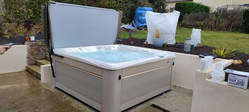 Spa blanc en cours d'installation, une main visible à gauche, de la signalétique à droite