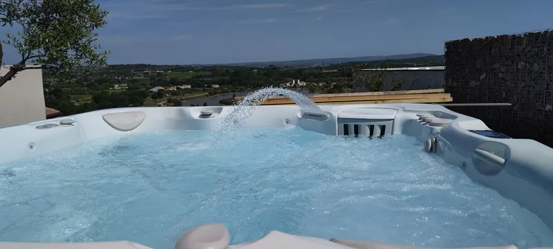 Spa blanc rempli d'eau claire sur le toit-terrasse, campagne verte au fond