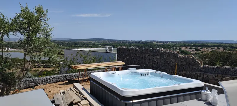 Spa rempli d'eau sur le toit-terrasse, panorama sur collines, champs et plan d'eau