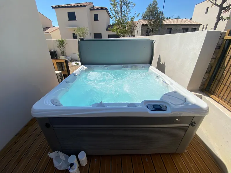 Spa bleu installé dans la cour patio, murs blancs autour