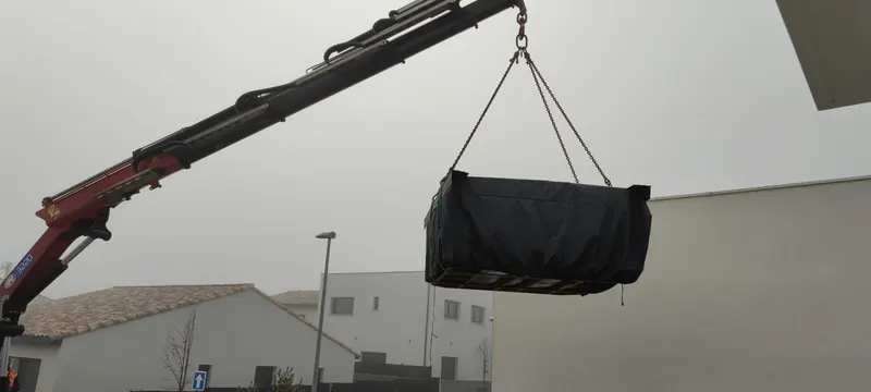 Spa noir et recouvert, soulevé par la grue pendant le levage