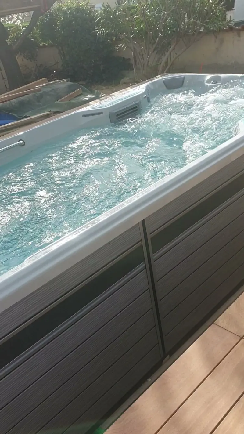 Spa à coque blanche, jets en marche, sur une terrasse en bois