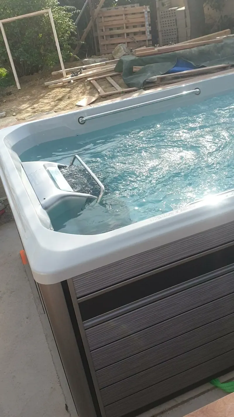 Spa rempli et en marche, habillage gris foncé, palettes au fond du jardin