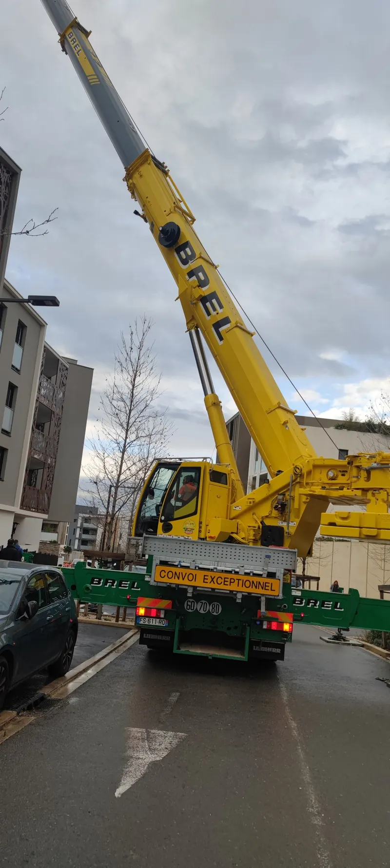Grue levant le spa noir au-dessus d'un bâtiment, en milieu urbain dense