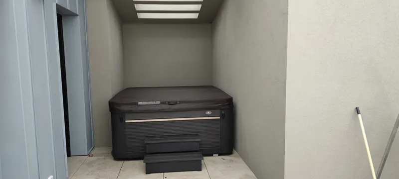 Vue d'ensemble du spa noir dans son abri couvert, à l'espace restreint