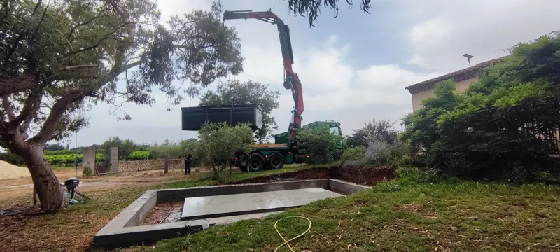 Spa noir suspendu à la grue au-dessus de la fondation excavée en béton