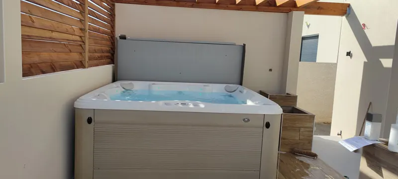 Spa blanc rempli d'eau, vu de haut en plein cadre, sous la pergola en bois