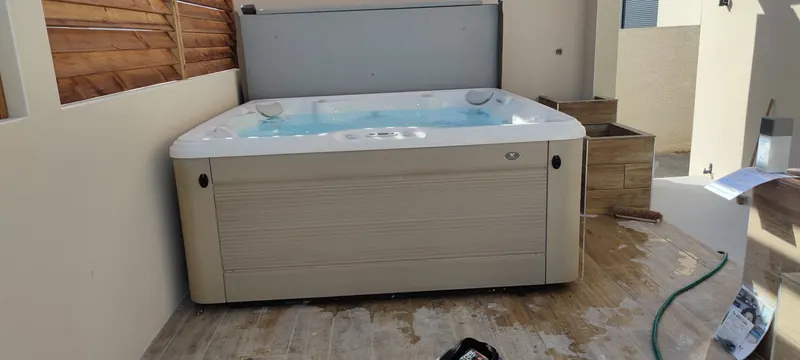 Spa blanc vu de face, sous la structure en bois, sur un sol carrelé