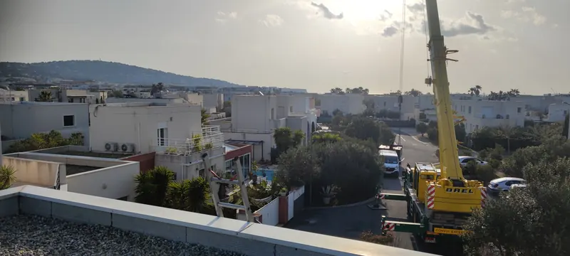 Spa soulevé par la grue au-dessus de l'agglomération, maisons blanches en contrebas
