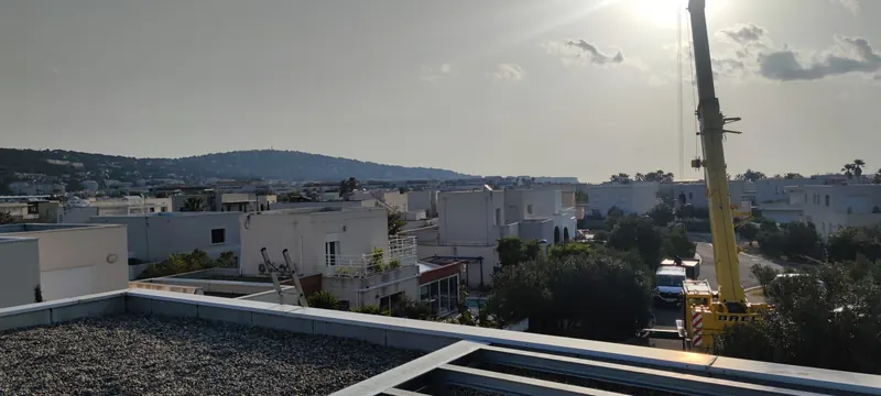 Structure grise destinée à recevoir le spa sur le toit-terrasse en béton, grue à côté