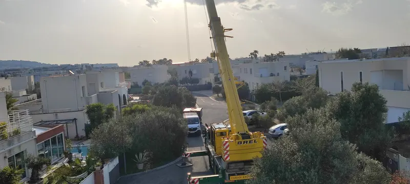 Vue aérienne d'ensemble du chantier avec la grue, l'immeuble et les alentours urbains
