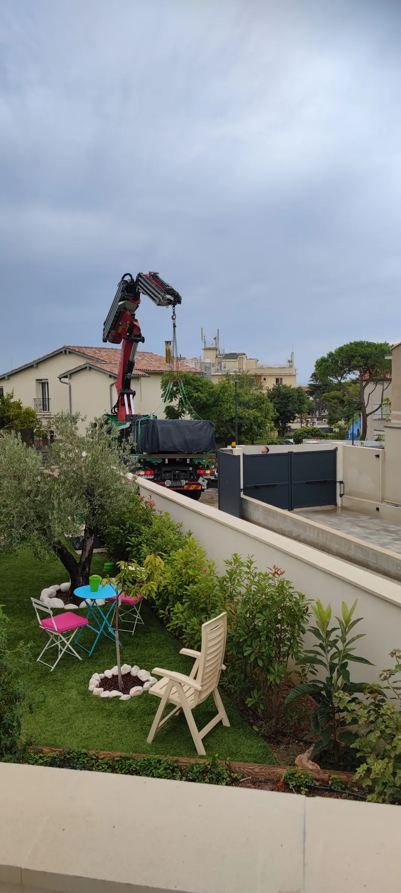 Grue qui lève un spa emballé au-dessus d'une cour de maison