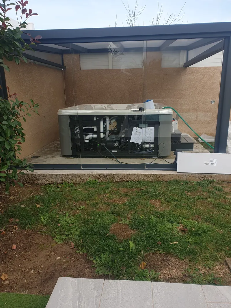 Spa sans habillage sous une pergola vitrée au fond d'un jardin à Thézan-lès-Béziers