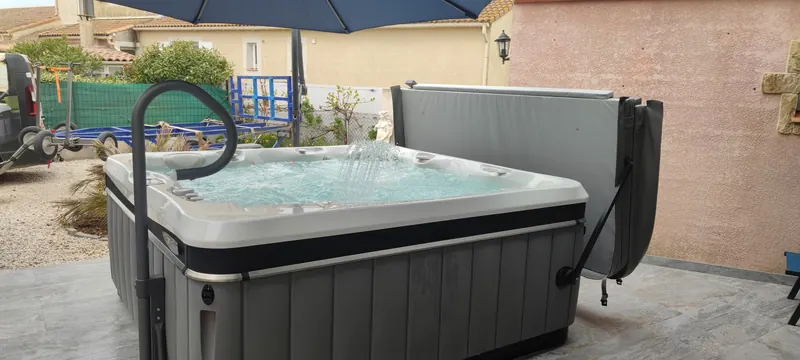 Spa noir et blanc sur la terrasse, accessoires de traitement de l'eau à côté