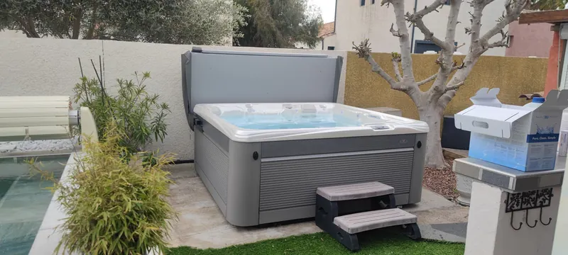 Spa blanc rempli d'eau turquoise, avec ses marches d'accès