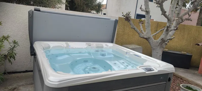 Spa blanc vu de côté, avec jardinière et arbre